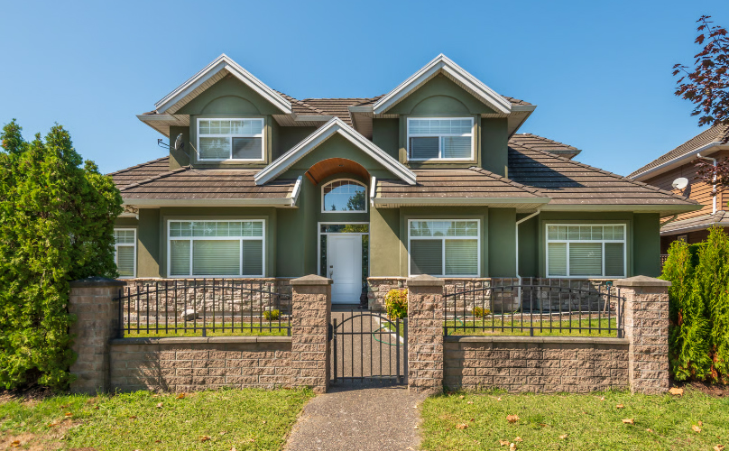 A two-story olive green house with stone accents and a manicured lawn in Ohio, representing property value for home equity loans.
