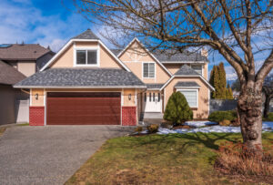 A two-story tan suburban home in Columbus, Ohio, with a brick-accented garage and a large tree in the foreground.