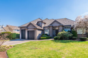 Modern single-family home with a green lawn and two-car garage representing home maintenance planning.