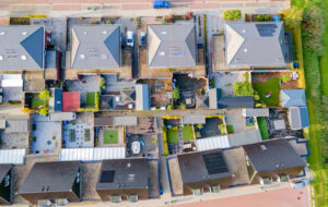 Aerial top-down view of residential houses with rooftops and solar panels.